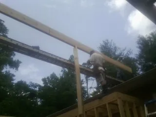 Carpenter setting a ridge beam over a new addition frame — Ice Dam Removal by Roofing Brothers in Burgess