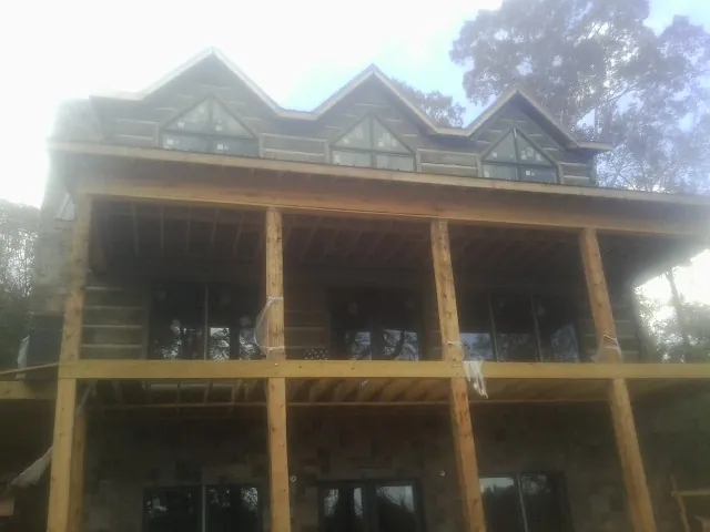 Dormers and porch framing on a large log home under construction — Roof Coating work by our crew in Burgess