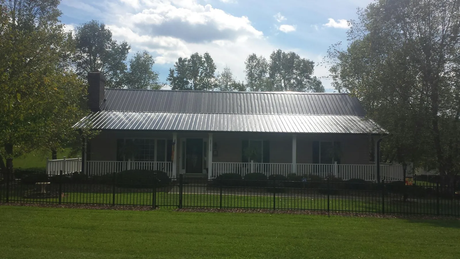 Gray metal roof on a brick ranch with a full width front porch — Gutter Guard Installation work by our crew in Burgess