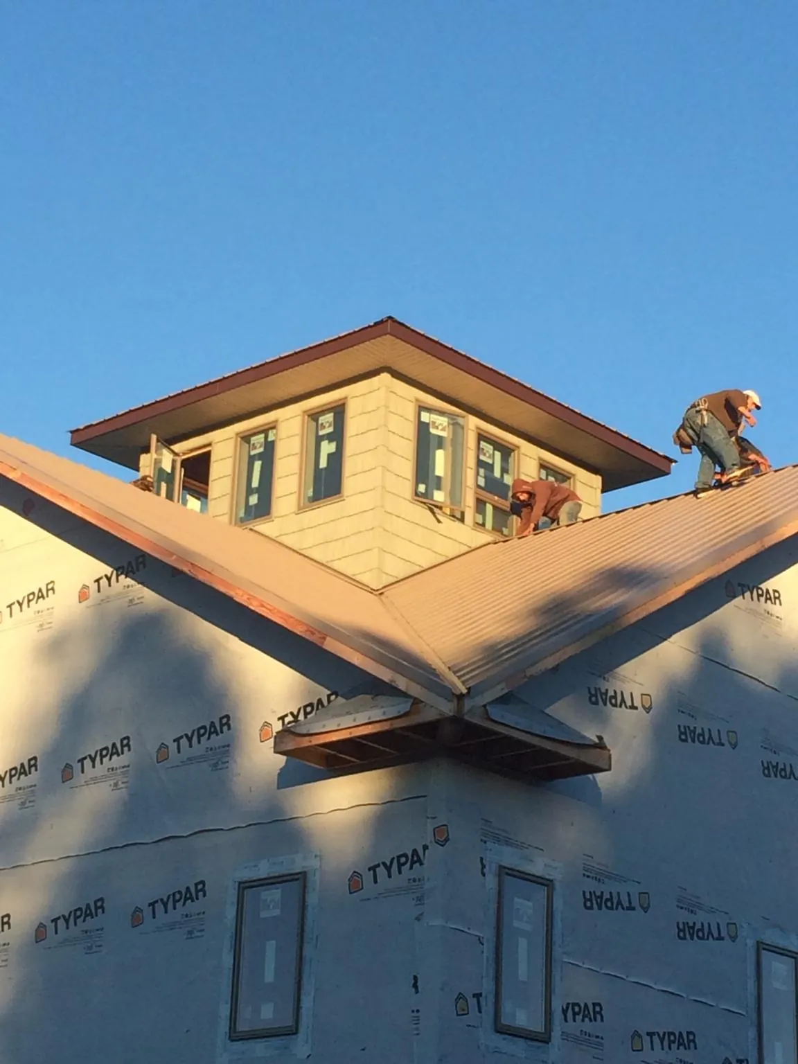 Roofers working around a rooftop cupola on a new metal roof at sunset — Roof Waterproofing in Burgess by Roofing Brothers